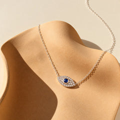 925 sterling silver evil eye necklace with a deep-blue center stone and shimmering zircon accents on an ivory sculptural display