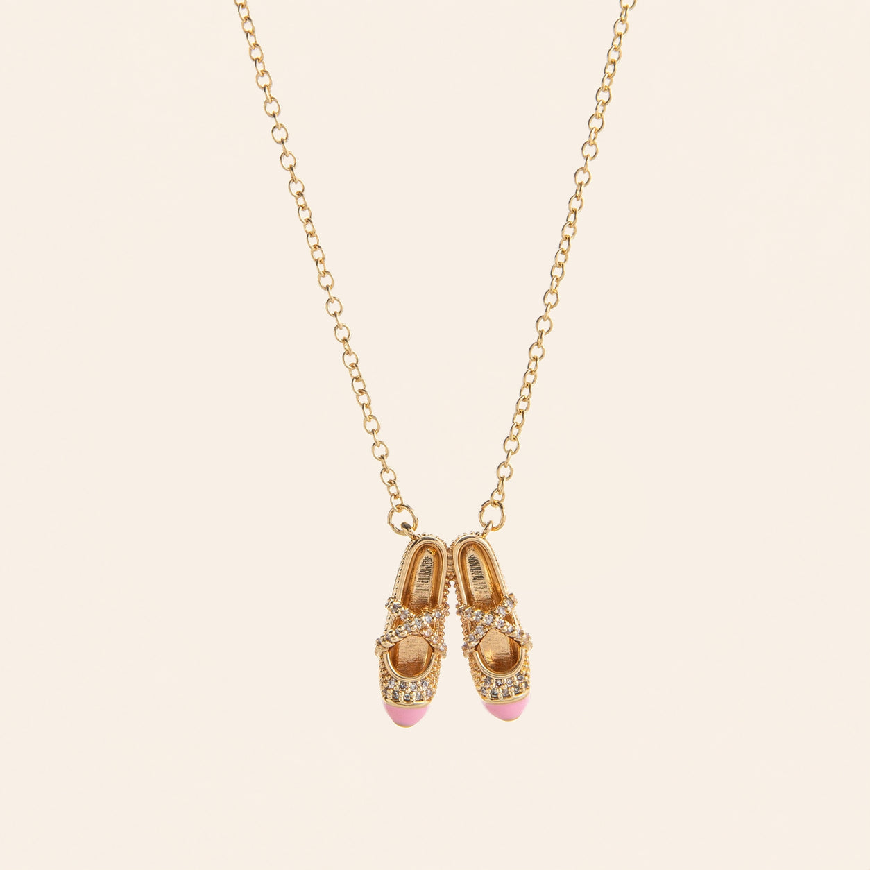 pink ballet shoes necklace in a jewelry box with gold chain and sparkling details