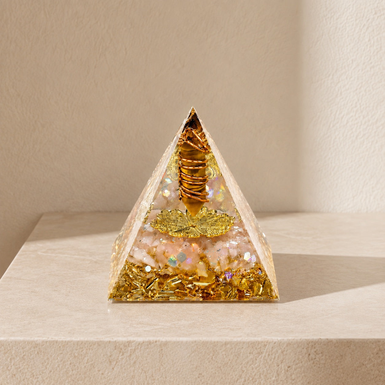 Tiger's Eye and citrine orgonite pyramid on a soft beige background