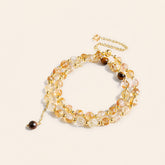 Citrine and Tiger’s Eye multi-strand bracelet with gold-tone chain and dangling stone charms on a cream background