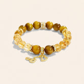 Tiger Eye and Golden Rutilated Quartz bracelet with gold-tone pavé spacers and dangling charms on a cream background