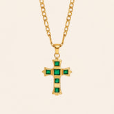 Green Zircon cross necklace with square-cut stones and a gold-tone Figaro chain on a cream background