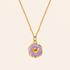 Gold-tone necklace with a colorful enamel star pendant on a warm ivory background