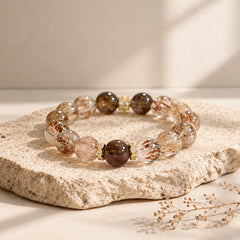 Black gold rutilated quartz beads with copper-brown needle-like inclusions beside dark smoky quartz stones