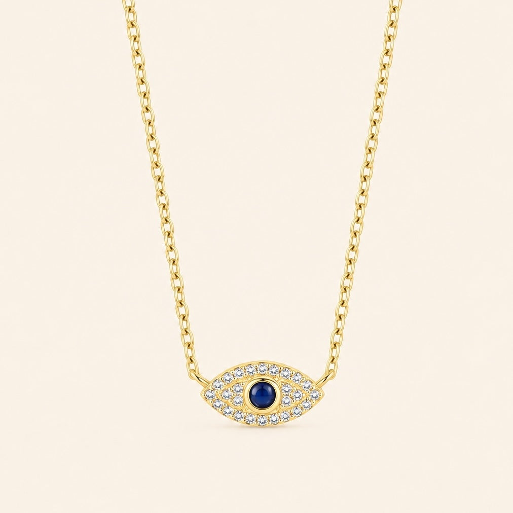 Gold-plated 925 sterling silver evil eye necklace with a blue center stone and zircon-set eye pendant against a light ivory background