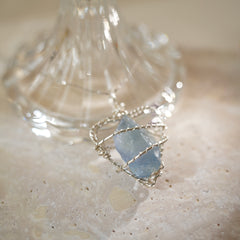 Natural aquamarine wire-wrapped necklace on stone background