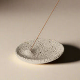 Wabi-sabi concrete incense holder in white on minimal wooden shelf
