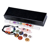 Set of chakra stones, bracelet, and crystal wand with black box on white background