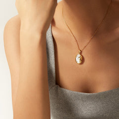 Gold necklace sun shell necklace symbolizing confidence and vitality with a pendant worn by a person against a neutral background