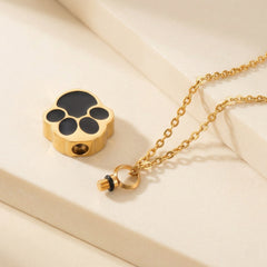 open gold paw print cremation necklace with funnel and filling tool on beige background