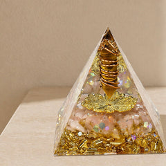 Abundance and wealth manifestation orgonite pyramid with tiger’s eye point, citrine chips, copper coil and gold details on a neutral background