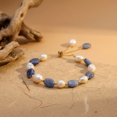 Blue aventurine and freshwater pearl bracelet with adjustable gold chain clasp on a warm neutral background