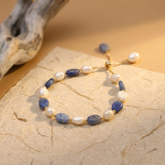 Blue aventurine and freshwater pearl bracelet with gold accents on a warm neutral background