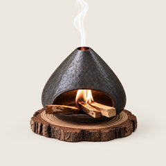 Fired Earth Brown ceramic Palo Santo and sage burner with burning wood and smoke on a natural wood slice