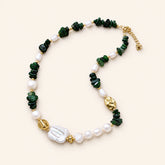 Green jade and freshwater pearl necklace with gold-plated accents arranged on a cream background