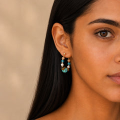 Close-up of a model wearing Tiger Eye and Turquoise earrings on a soft beige background
