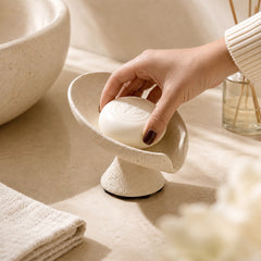 Hand placing soap into a beige bathroom soap holder tray.