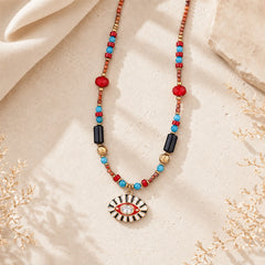 Evil Eye pendant necklace with red agate, turquoise, onyx and hematite beads styled on cream fabric