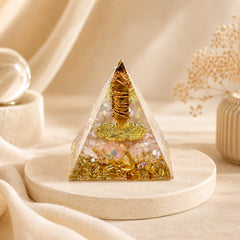Abundance and wealth manifestation orgonite pyramid with tiger’s eye point, citrine chips, copper coil and gold details on a neutral background