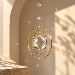 Side view of Golden Orbit clear quartz suncatcher with golden circular frame catching sunlight and casting rainbow prisms