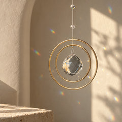 Golden Orbit clear quartz window suncatcher with balanced circular frame and soft rainbow reflections in sunlight