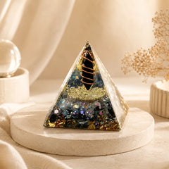 Obsidian and labradorite orgonite pyramid with copper coil and gold details styled on a soft beige crystal decor display