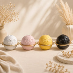 Four planet-shaped ceramic pet urns in white, pink, yellow and black