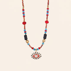 Evil Eye gemstone necklace with red agate, turquoise, black onyx and hematite beads on a cream background