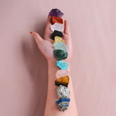Colorful raw chakra stones aligned on an arm for meditation and healing rituals