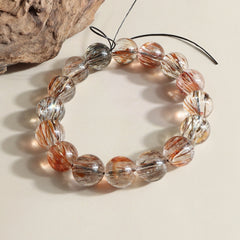 close up of natural black gold rutilated quartz bracelet with glossy round crystal beads