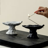 Hand placing incense stick into handmade ceramic burner – minimalist ritual
