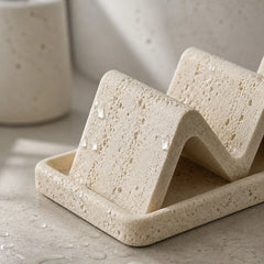 Close-up of porous natural sandstone soap dish with wave-shaped drainage design