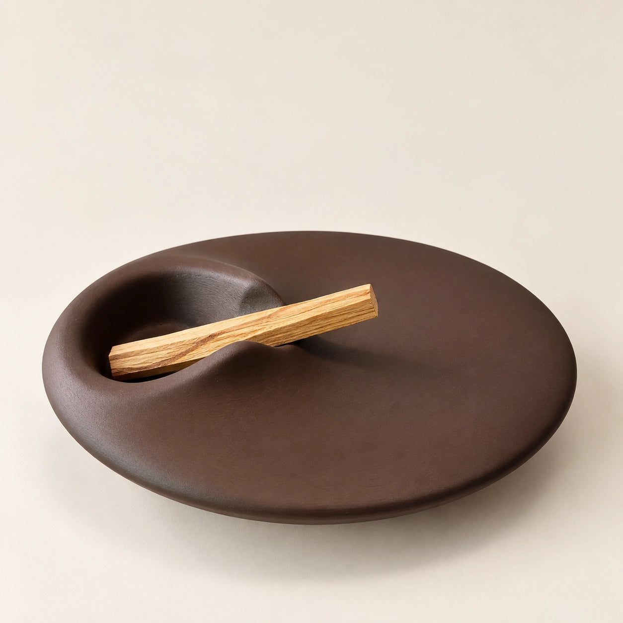 Angled view of a minimalist concrete Palo Santo holder with one unlit natural wood stick