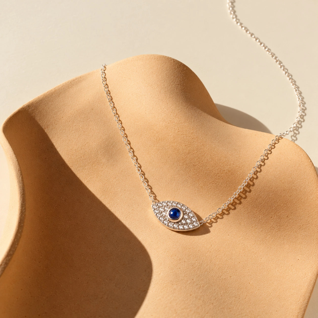 925 sterling silver evil eye necklace with a deep-blue center stone and shimmering zircon accents on an ivory sculptural display