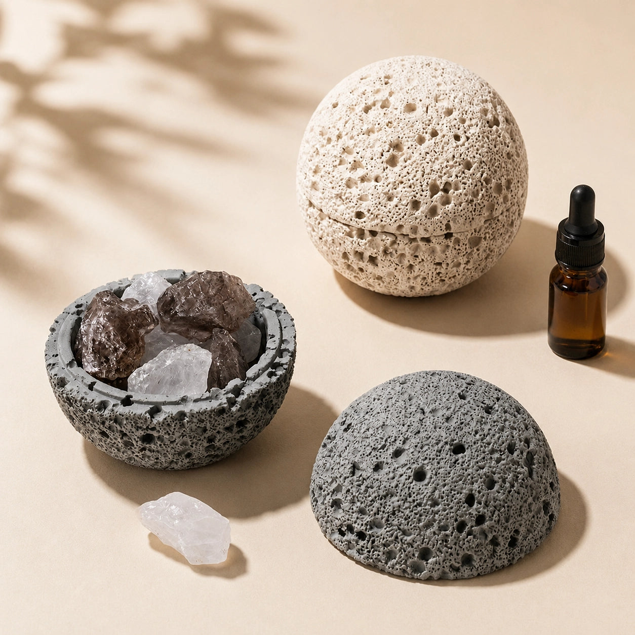 Grey crystal cleansing bowl with quartz beside a closed beige volcanic-texture aroma bowl