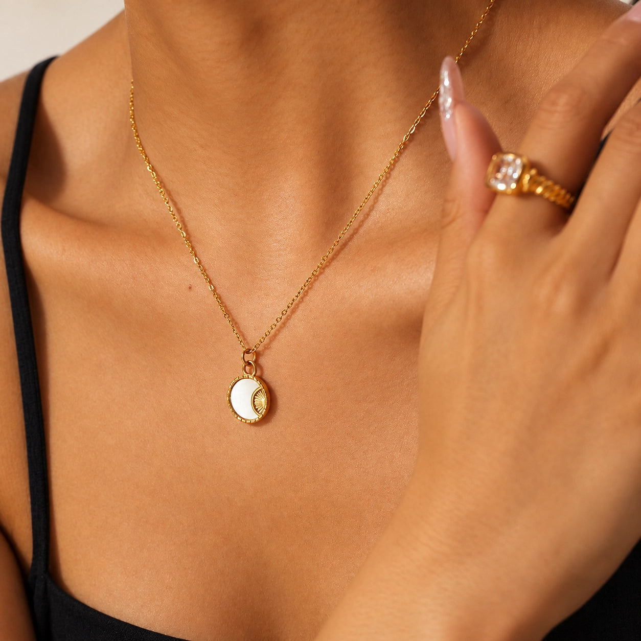 Close-up of model wearing a gold-tone shell pendant necklace with a hand near the neck, showing everyday necklace styling