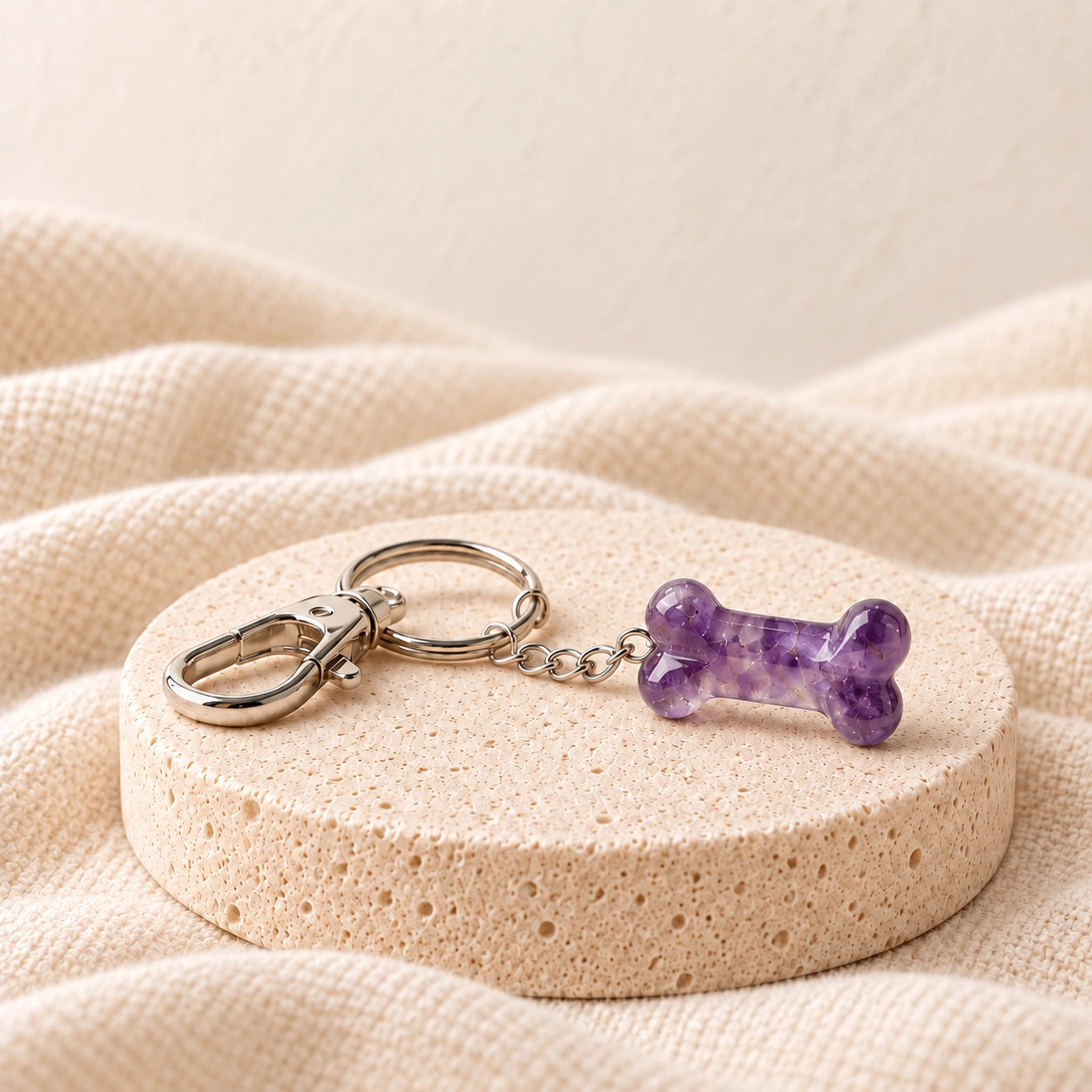Amethyst natural stone pet bone charm with silver keyring on a warm ivory stone display
