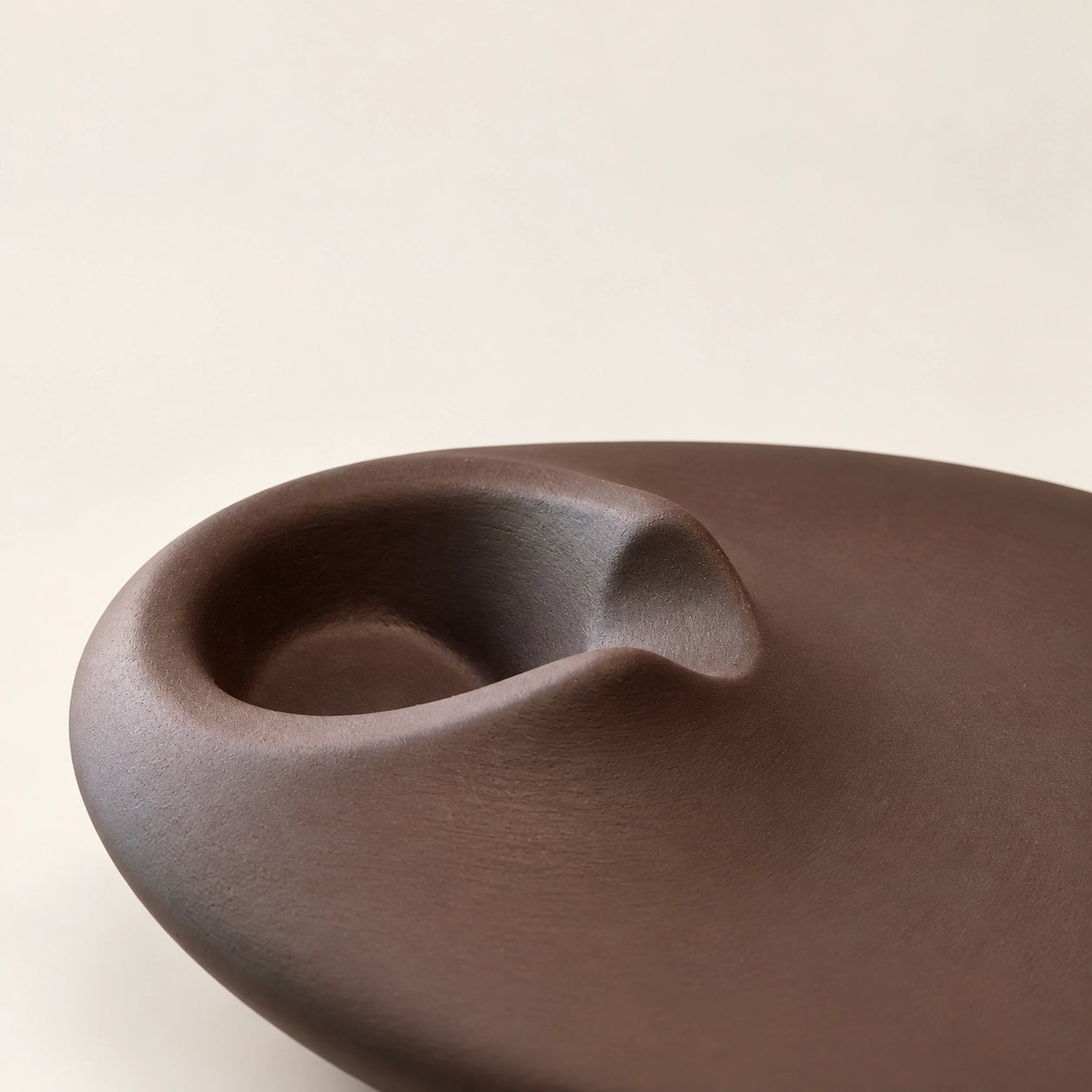Close-up detail of the matte concrete surface and recessed curve of a brown Palo Santo holder