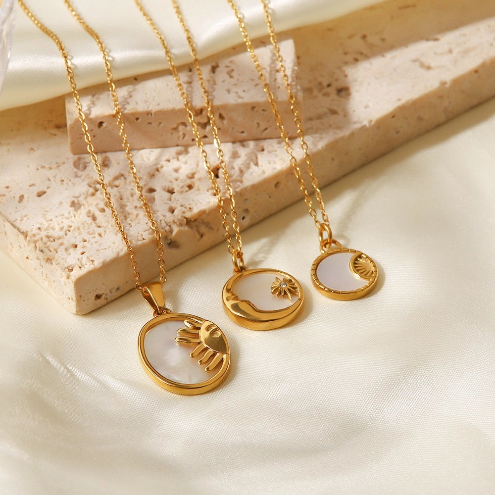 Three Sun and Moon shell pendant necklace styles displayed on soft fabric