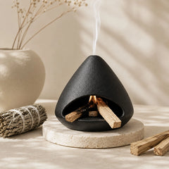Close view of black ceramic sage burner with open hearth, Palo Santo sticks and top smoke vent
