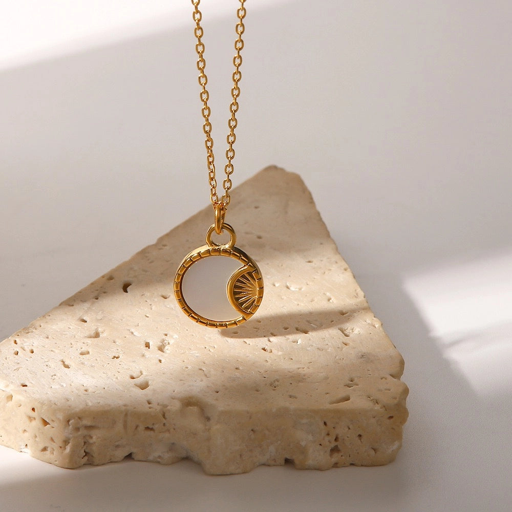Small Sun and Moon shell pendant necklace displayed on stone