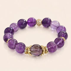 Uruguayan Amethyst bracelet with deep purple crystal beads and gold-tone accents on a cream background