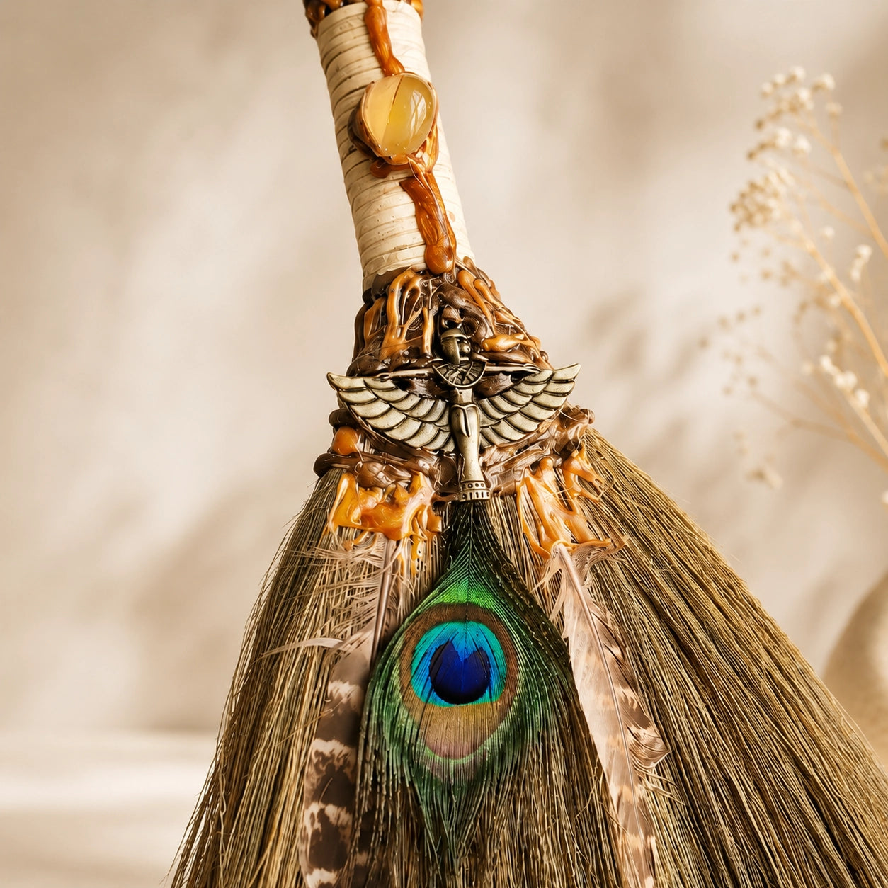 Close-up of handmade Peacock Feather Witch Broom with natural crystal, peacock feather, charm detail, and handwoven straw.