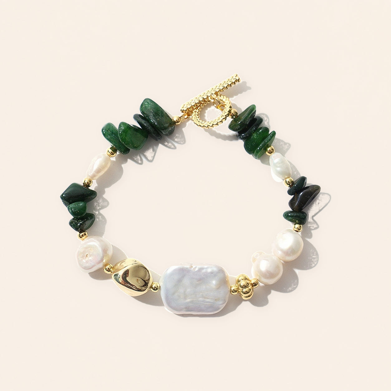 Green jade and freshwater pearl bracelet with gold-plated accents on a cream background