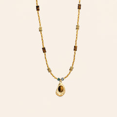 Tiger’s Eye pendant necklace with 18K gold-plated beaded chain and teal stone accents on a cream background