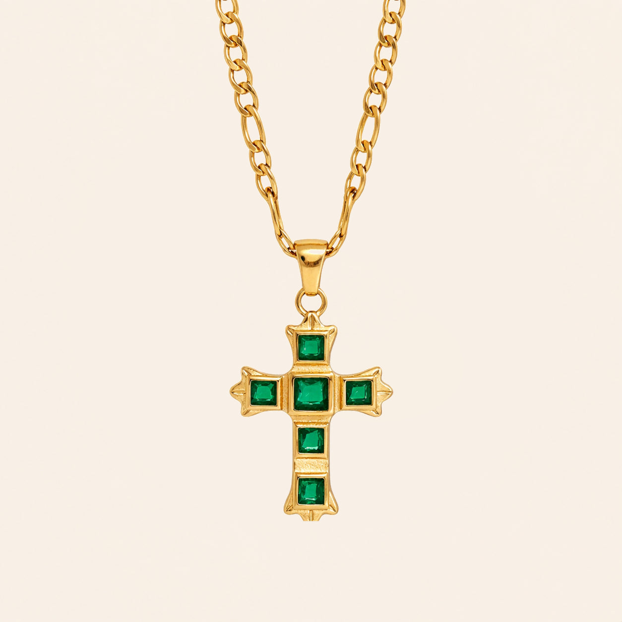 Green Zircon cross necklace with square-cut stones and a gold-tone Figaro chain on a cream background