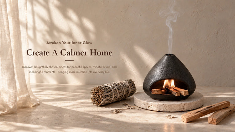 Black ceramic palo santo and sage burner with smoke, bundled sage, and palo santo sticks in a warm sunlit neutral interior.