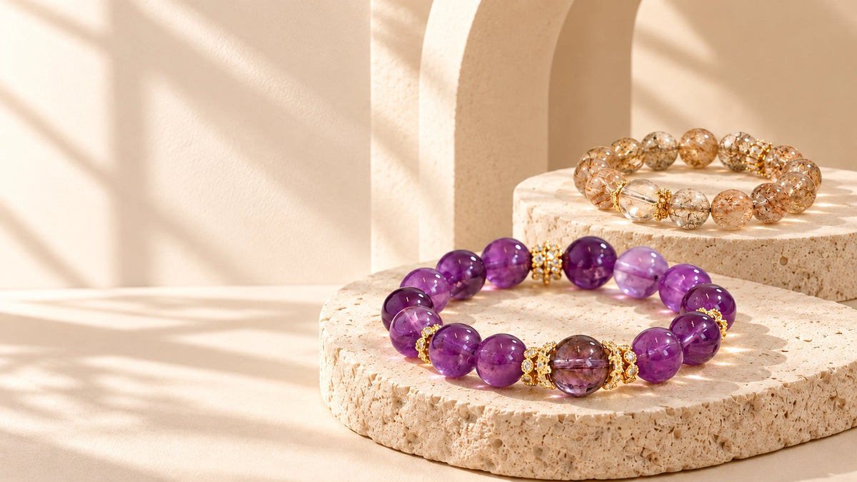 Amethyst and golden-toned crystal bracelets displayed on sculptural ivory stone pedestals