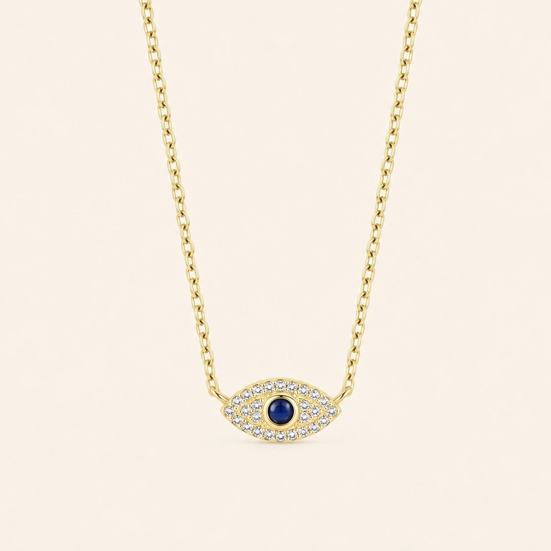 Gold-plated 925 sterling silver evil eye necklace with a blue center stone and zircon-set eye pendant against a light ivory background