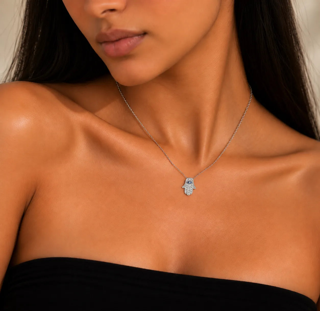 Model wearing 925 sterling silver Hamsa hand necklace with blue evil eye and petite zircon-set pendant
